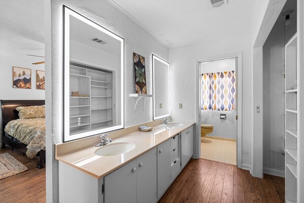 A modern bathroom with two sinks, a large mirror, and a walk-in shower.
