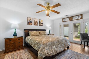 A bedroom with a bed, wooden nightstands, a ceiling fan, and a view through a glass door. - Cosby Mountain Lodge 4 Bedroom Home (Cosby)