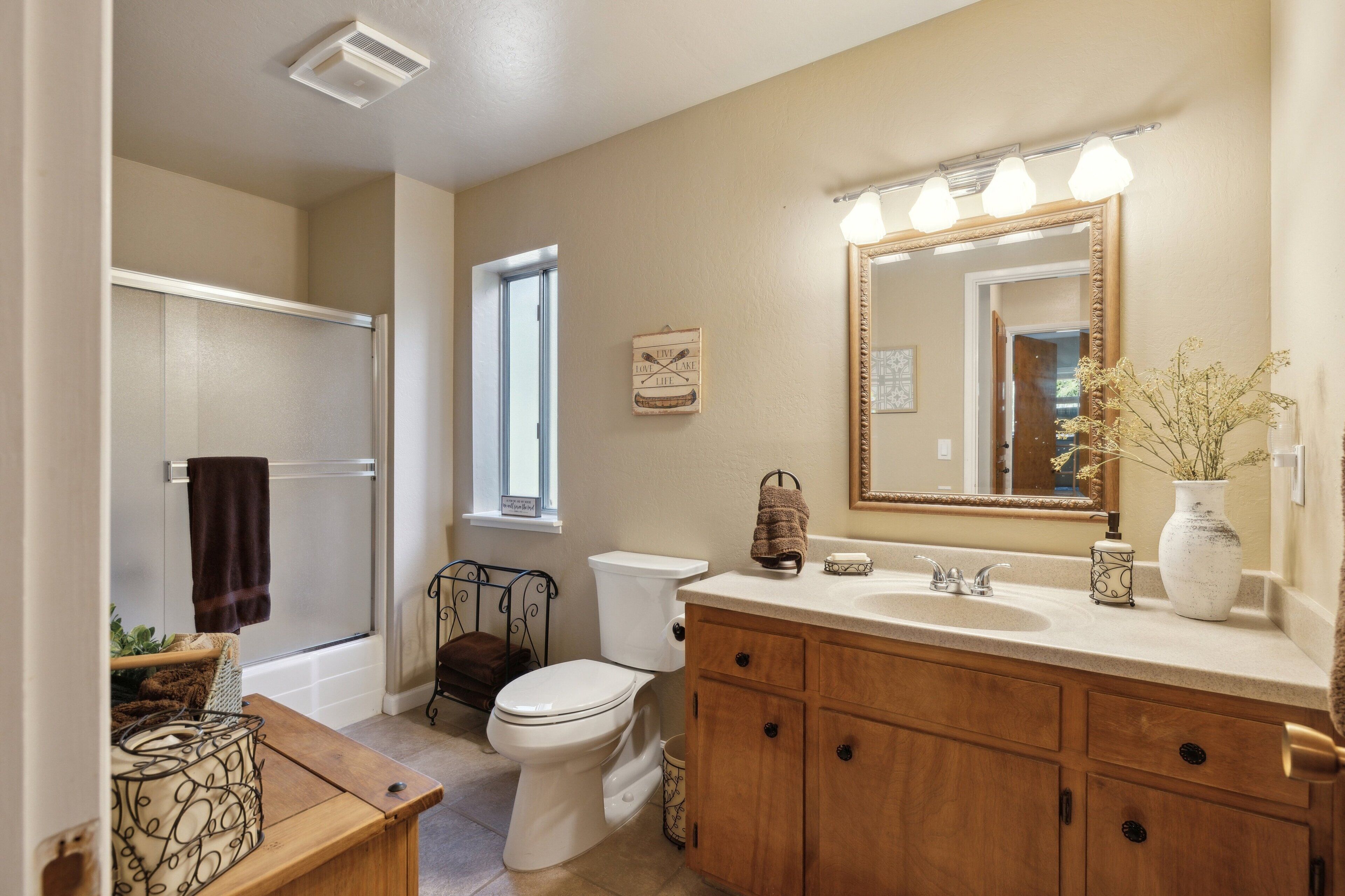A bathroom with a toilet, sink, vanity, and a shower area.