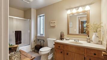 A bathroom with a toilet, sink, vanity, and a shower area.