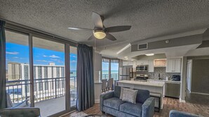 A modern apartment with a balcony, a living room with a sofa and coffee table, and a kitchen area. - 1707 Brighton, impressively remodeled, 3 bedroom ocean view 3 Condo (Myrtle Beach)