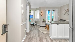A modern kitchen with white cabinets, a refrigerator, and a dining area with a table and chairs. - Myrtle Beach Resort RT1205 (Myrtle Beach)