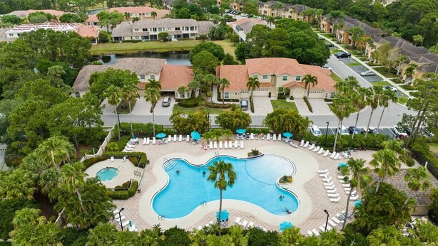 A resort with a large swimming pool, palm trees, and a golf course in the background. - Right Direction Rentals Studio Villa 8419 (Port St. Lucie)