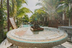 A round table with a mosaic design, surrounded by chairs, in a tropical outdoor setting with palm trees. - Valentina Resort & Spa (Phu Quoc)