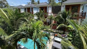 Un resort con varias villas, una piscina y exuberante vegetación tropical.