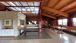 A spacious room with a high ceiling, a stone fireplace, a long wooden table, and a staircase leading to an upper level. - Locanda Gulfi (Chiaramonte Gulfi)