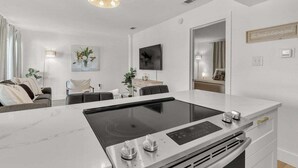 A modern kitchen with a central island, a dining area with a table and chairs, and a living room with a sofa and decorative items. - Boho Retreat 2003-Near Lake Aladdin-Sleeps 4 (Destin)