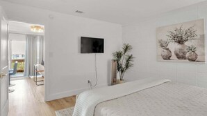 A modern bedroom with a bed, a television, a potted plant, and a painting on the wall. - Boho Retreat 2003-Near Lake Aladdin-Sleeps 4 (Destin)