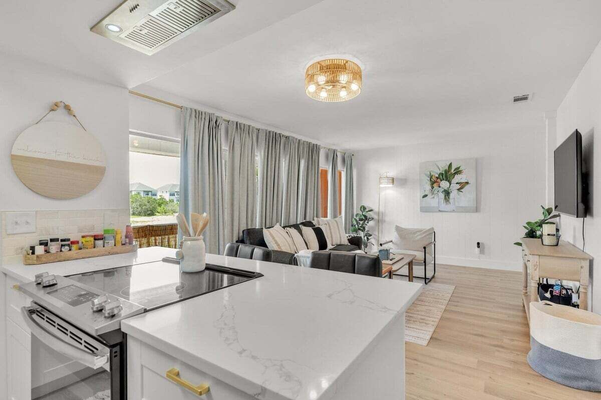 Eine moderne Küche mit einer Marmorinsel, ein Essbereich mit einer Couch und ein Wohnzimmer mit Fernseher.