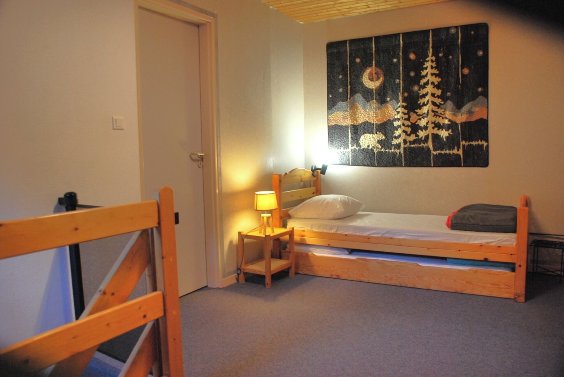 Een knus slaapkamer met een enkel bed, een nachtkastje, een lamp en een wanddecoratie.