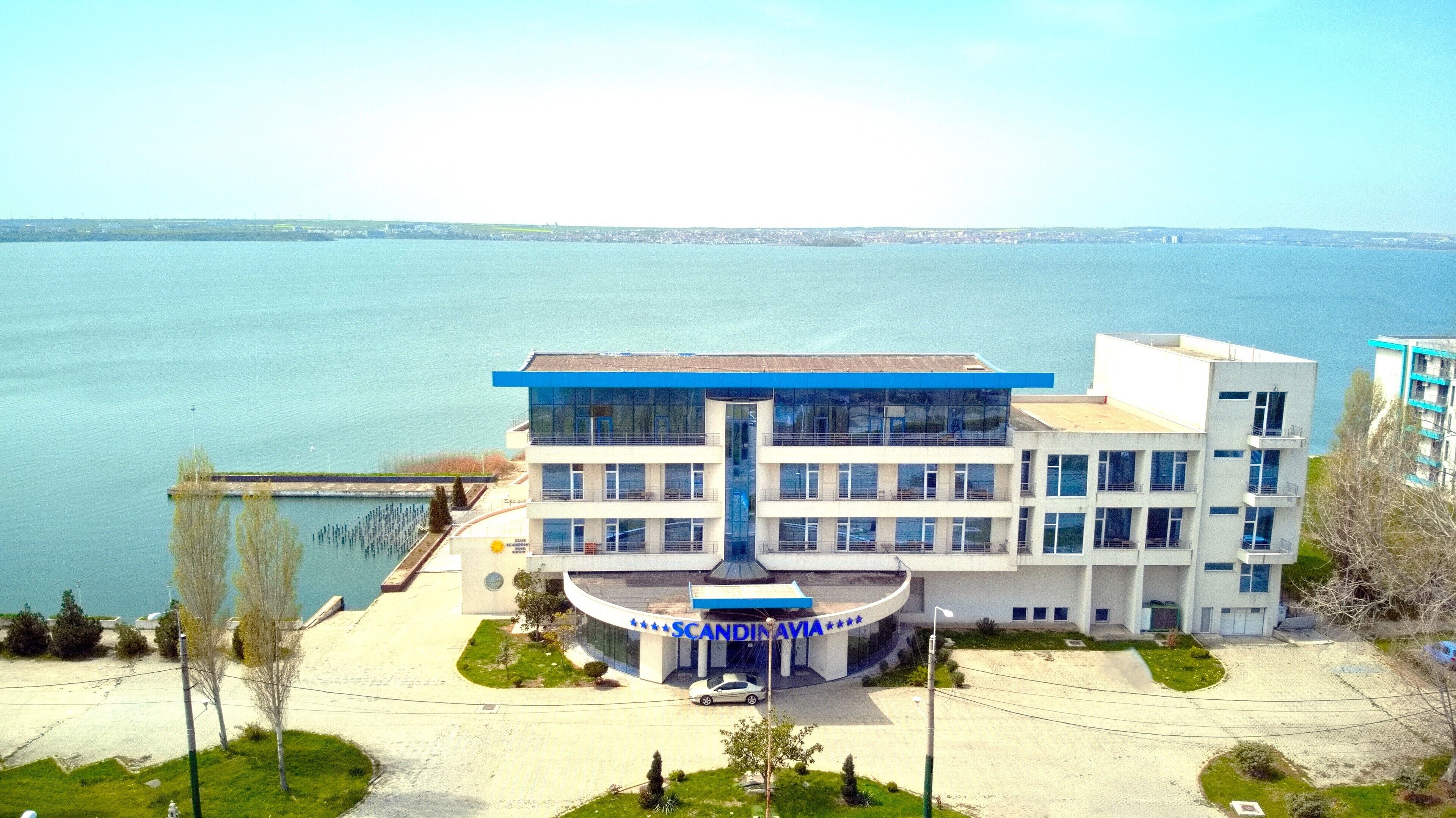 A modern building with a central atrium, a waterfront view, and a parking area.