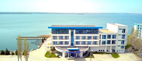 A modern building with a central atrium, a waterfront view, and a parking area.