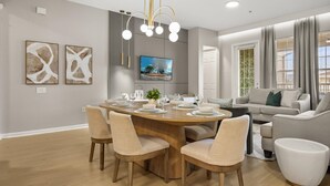 A modern living room with a dining area, a flat-screen TV, and a sofa with cushions. - Upstay: Renovated Vista Cay Condo, Epic Universe (Orlando)