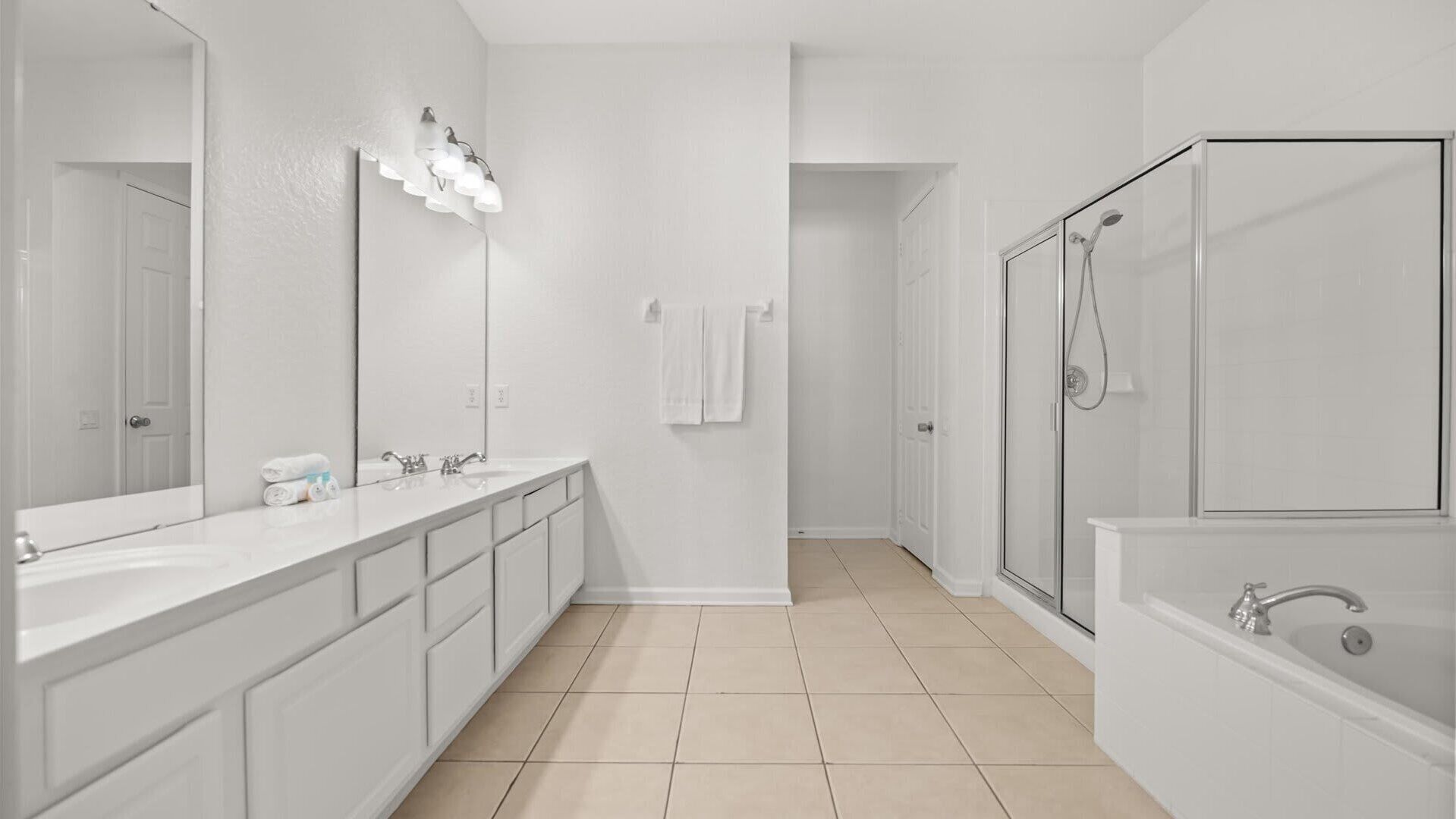 A modern bathroom with a large mirror, two sinks, a shower, and a bathtub.