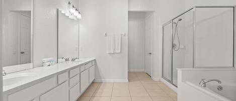 A modern bathroom with a large mirror, two sinks, a shower, and a bathtub.