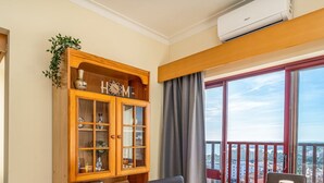 A room with a large window, a wooden cabinet, and a balcony with a view of a cityscape. - #256 Sea & Sun View by Home Holidays (Portimão)
