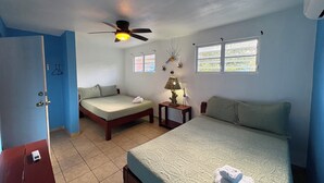 Un dormitorio con una cama, una cama individual, un escritorio, una lámpara y un ventilador de techo.