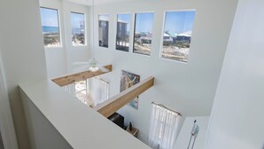 Une pièce aux hauts plafonds, dotée de grandes fenêtres, d’une poutre en bois et d’un ventilateur de plafond.