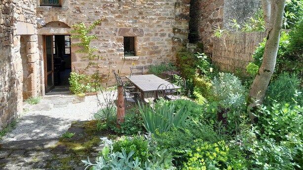 A stone building with a wooden table and chairs in a garden area. - Large medieval village house, pets welcome, private pool. (Salles)