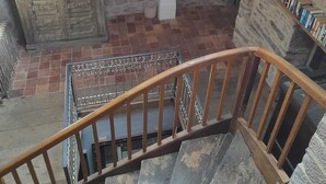 A staircase with wooden railings leading to a stone floor, a patterned rug, and a bookshelf with books. - Large medieval village house, pets welcome, private pool. (Salles)