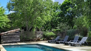 A rectangular swimming pool with a stone border, surrounded by a wooden deck and a stone wall. - Large medieval village house, pets welcome, private pool. (Salles)