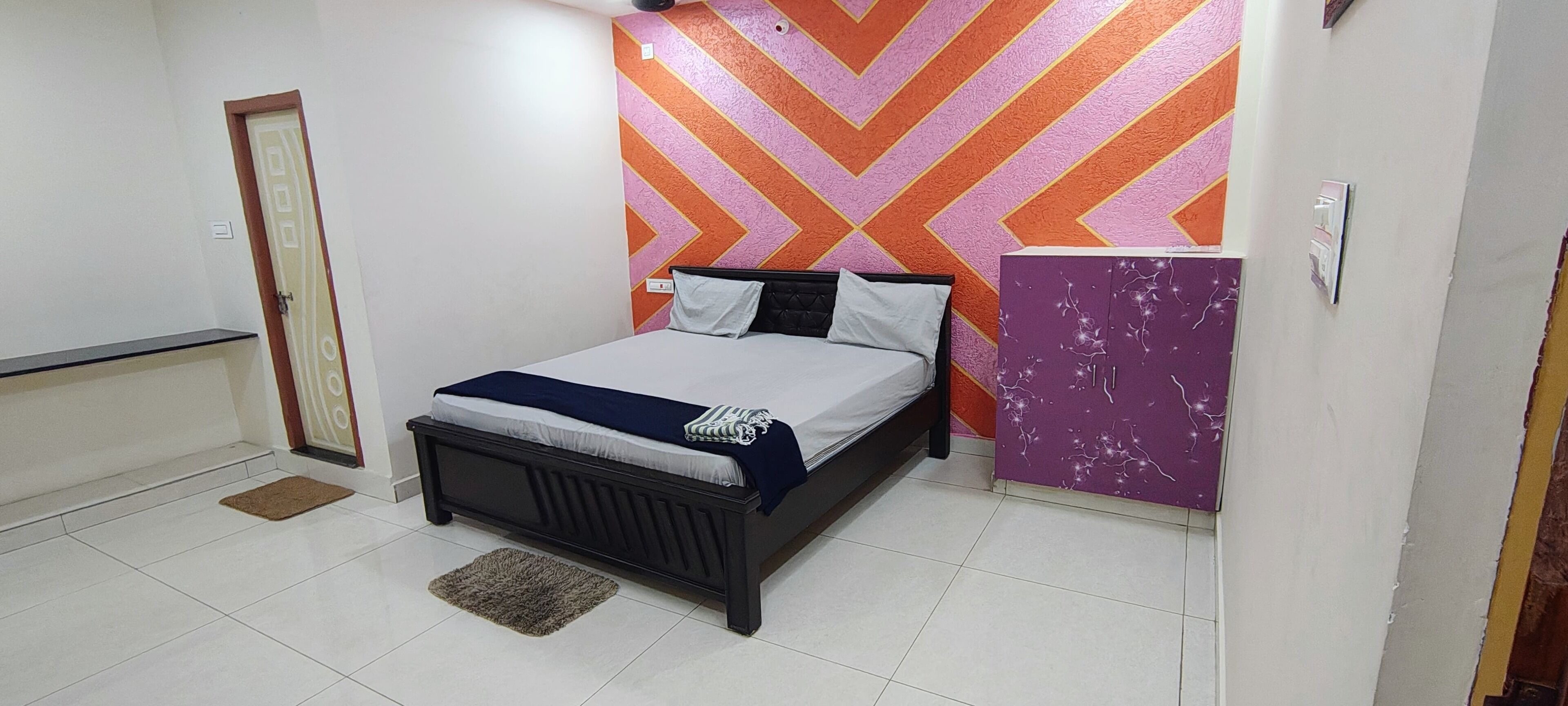 A bedroom with a bed, a wardrobe, and a door.