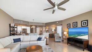 A spacious living room with a large flat-screen TV, a ceiling fan, and a view of the ocean. - Caribe Resort 1206B by Liquid Life (Orange Beach)