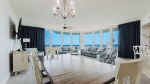 Amplia sala de estar con una gran mesa de madera, dos sofás y vista al océano.