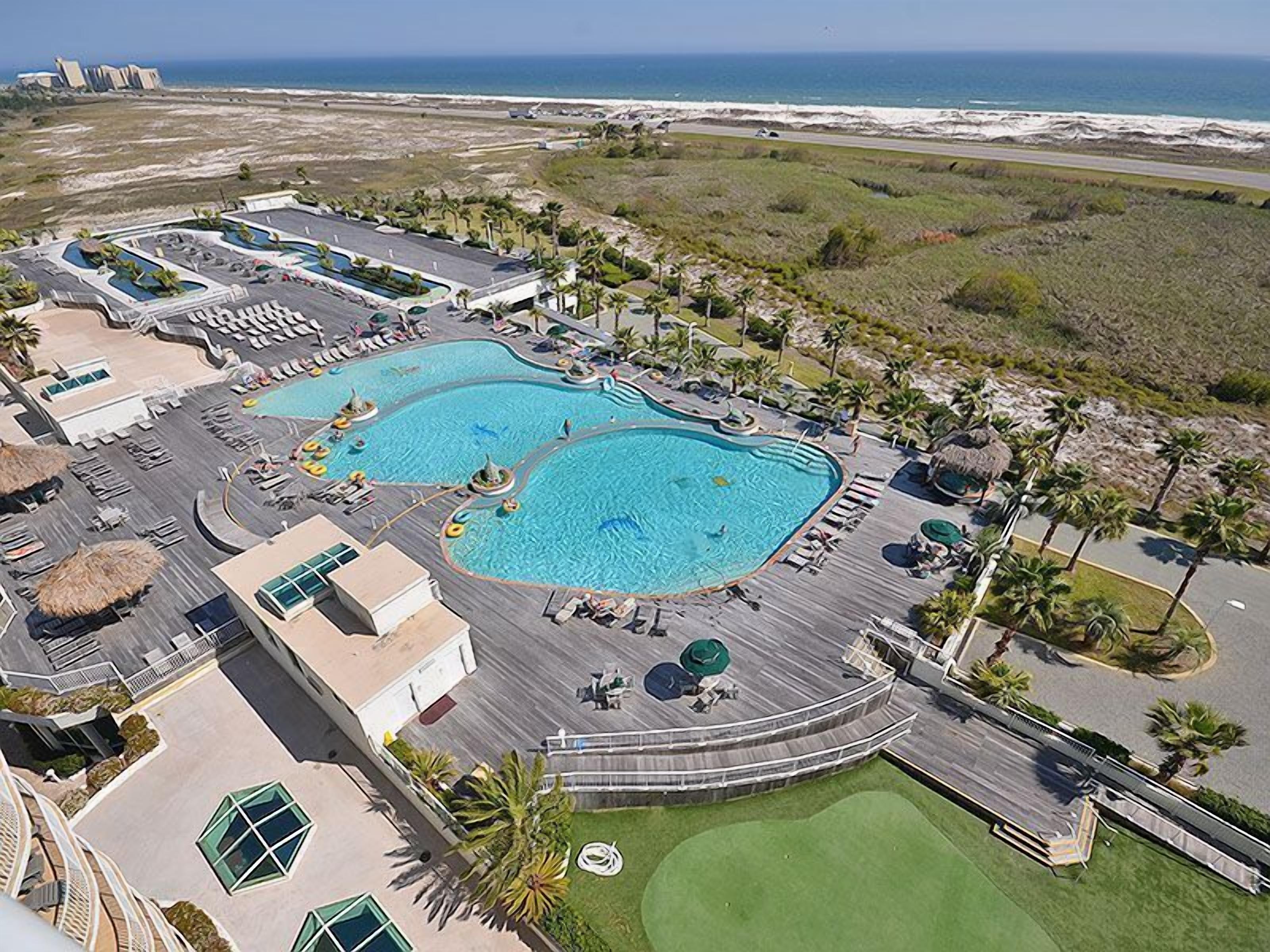 Un resort con varias piscinas, un campo de golf y vista al océano.