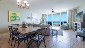 Amplia sala de estar con una mesa de comedor, sillas y vista al océano a través de grandes ventanales.