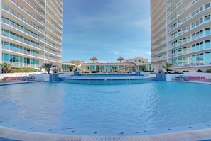 Area piscina di un hotel con una fontana centrale, diversi balconi e lettini.
