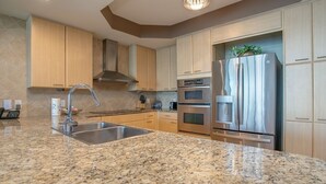 A modern kitchen with granite countertops, stainless steel appliances, and wooden cabinets.