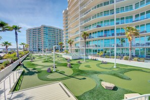 Ein Resort mit Golfplatz, einem großen Gebäude mit Balkonen und Palmen.