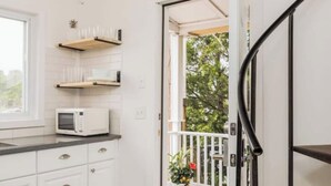 A kitchen with white cabinets, a microwave, and wooden shelves. - Ocean Boulevard North, 3 min walk to beach! (Rye)