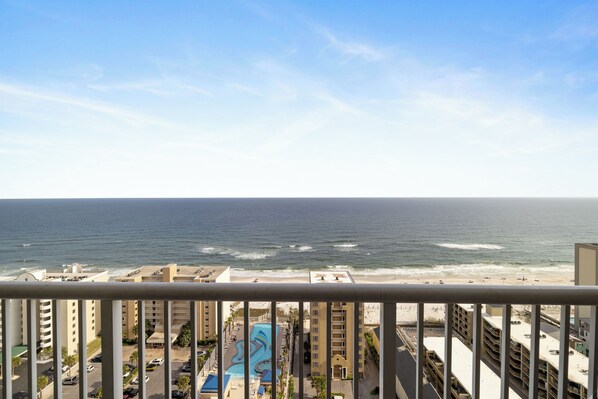 Vista de un hotel frente a la playa con piscina, varios pisos y una playa al fondo.