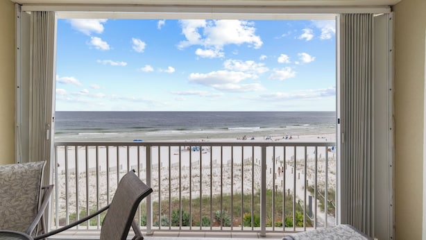 A balcony with a view of the beach, a chair, and a small table. - Marlin Key 3E by Liquid Life (Orange Beach)
