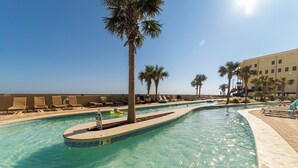 Una piscina con agua cristalina, rodeada de palmeras y sillones de descanso.