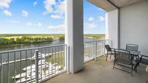 Un balcón con vista a un río y un puerto deportivo, con una mesa y sillas.