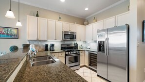 Una cocina con encimeras de granito, electrodomésticos de acero inoxidable y armarios de color claro.