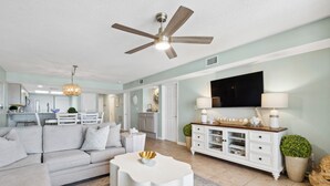 A spacious living room with a grey sofa, a white coffee table, and a ceiling fan.