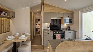 A compact kitchen with a stove, microwave, and sink. There is a dining area with a table set for four.
