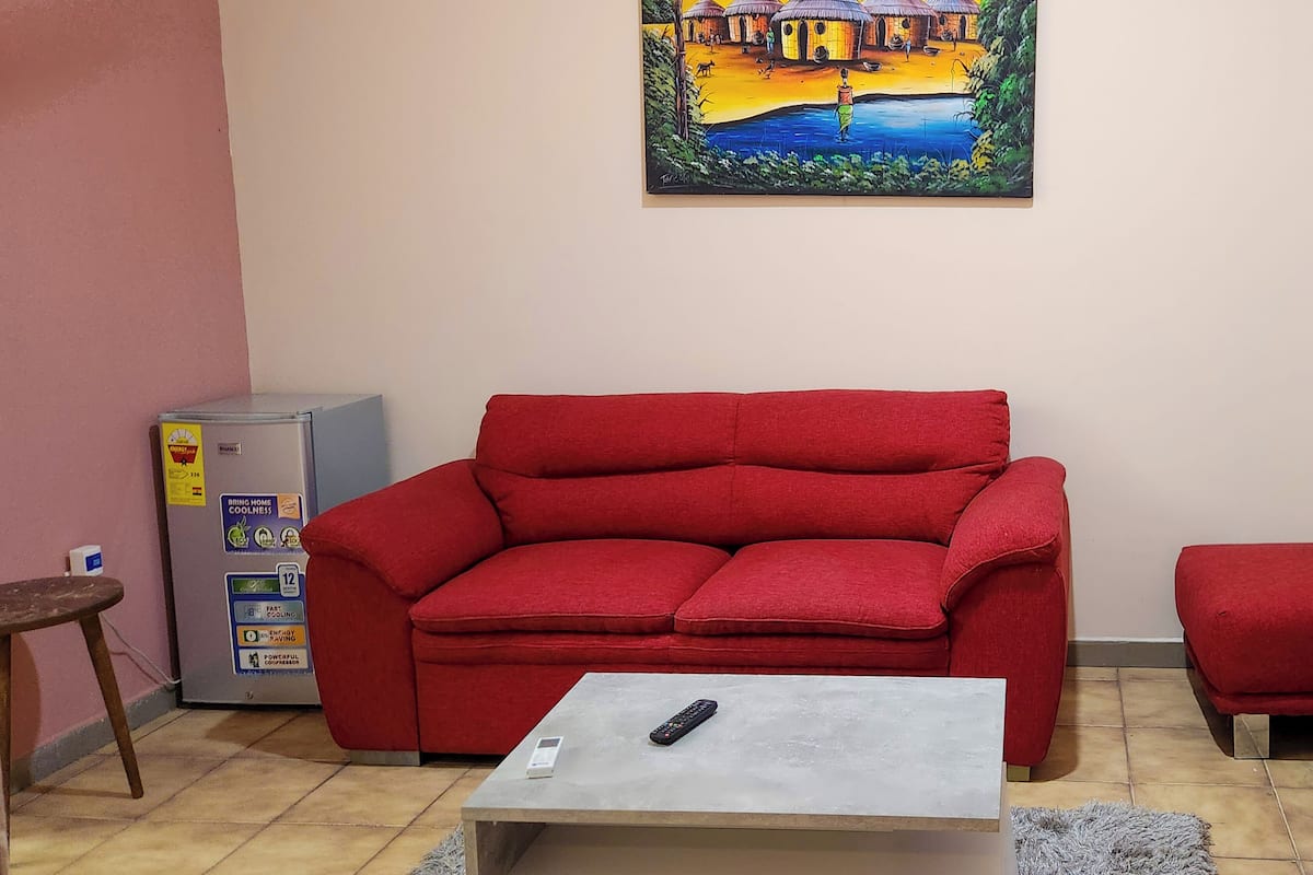 Un salón con un sofá rojo, una mesita y un cuadro en la pared.