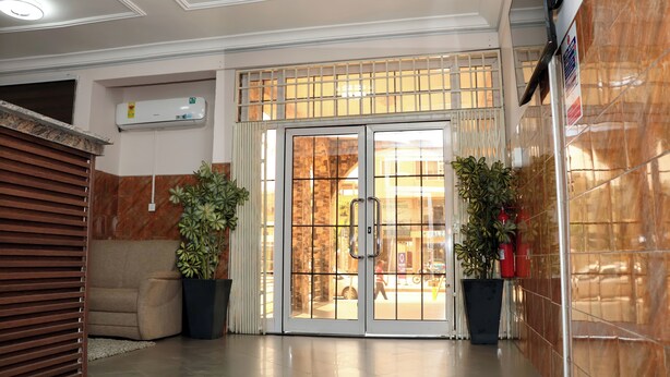 A lobby with a glass door entrance, a ceiling fan, a potted plant, and a sofa. - GSM Crown Inn Hotel  (Ogbodjo)