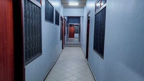 A narrow hallway with tiled flooring and walls painted in a light blue color. - GSM Crown Inn Hotel  (Ogbodjo)