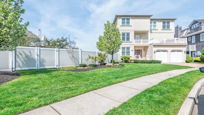 A two-story residential building with a front lawn, a pathway, and a garage.