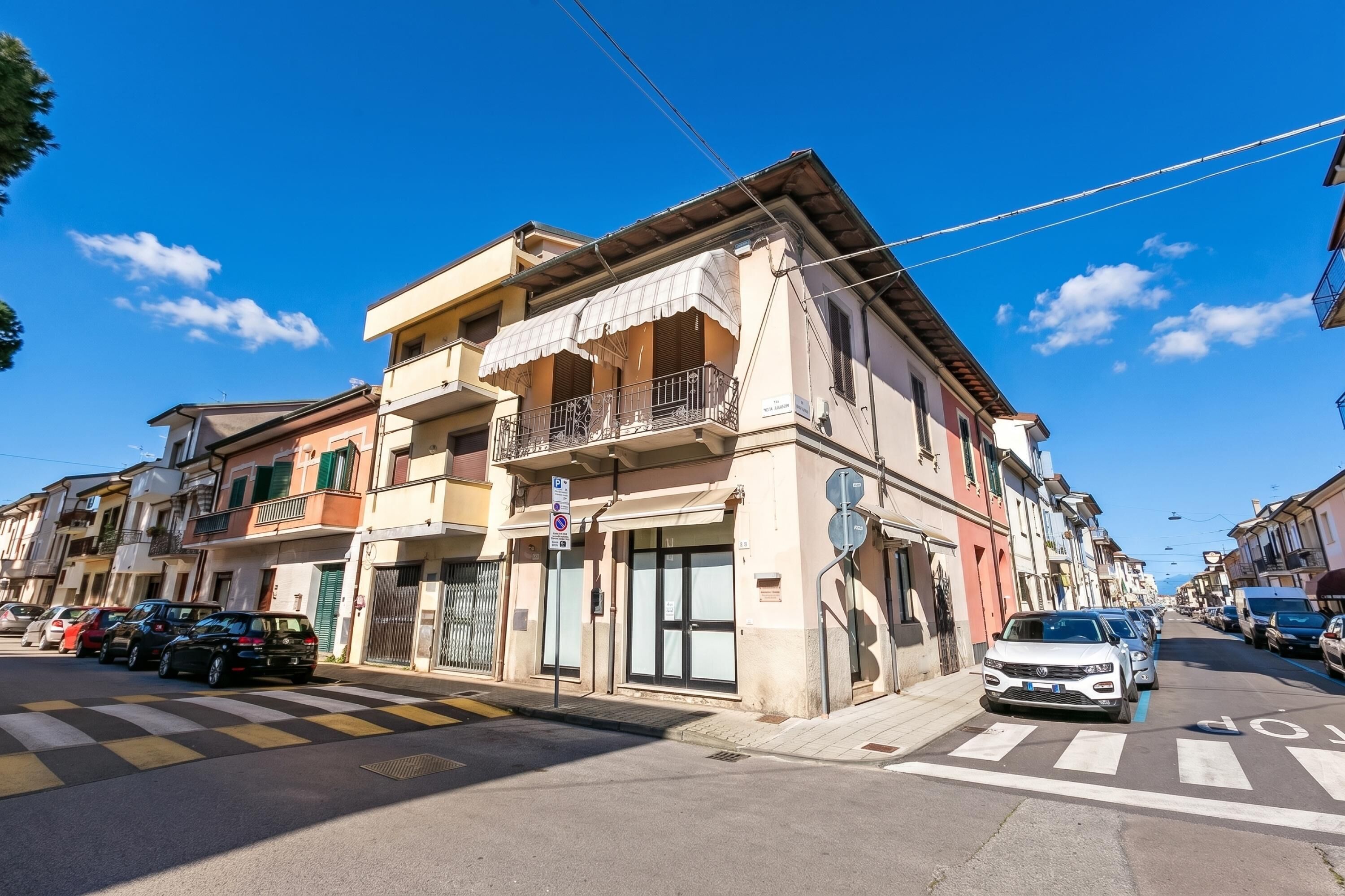 Un immeuble à plusieurs étages doté de balcons, d’un parking et surplombant un ciel bleu dégagé.