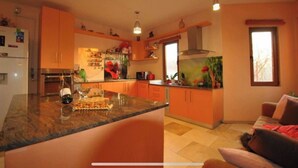 A modern kitchen with orange cabinets, a marble countertop, and a fish tank. - Pink Garden Events Advance Notice Required (Giarmata)