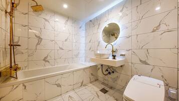 A bathroom with a bathtub, a sink with a mirror, and a toilet.