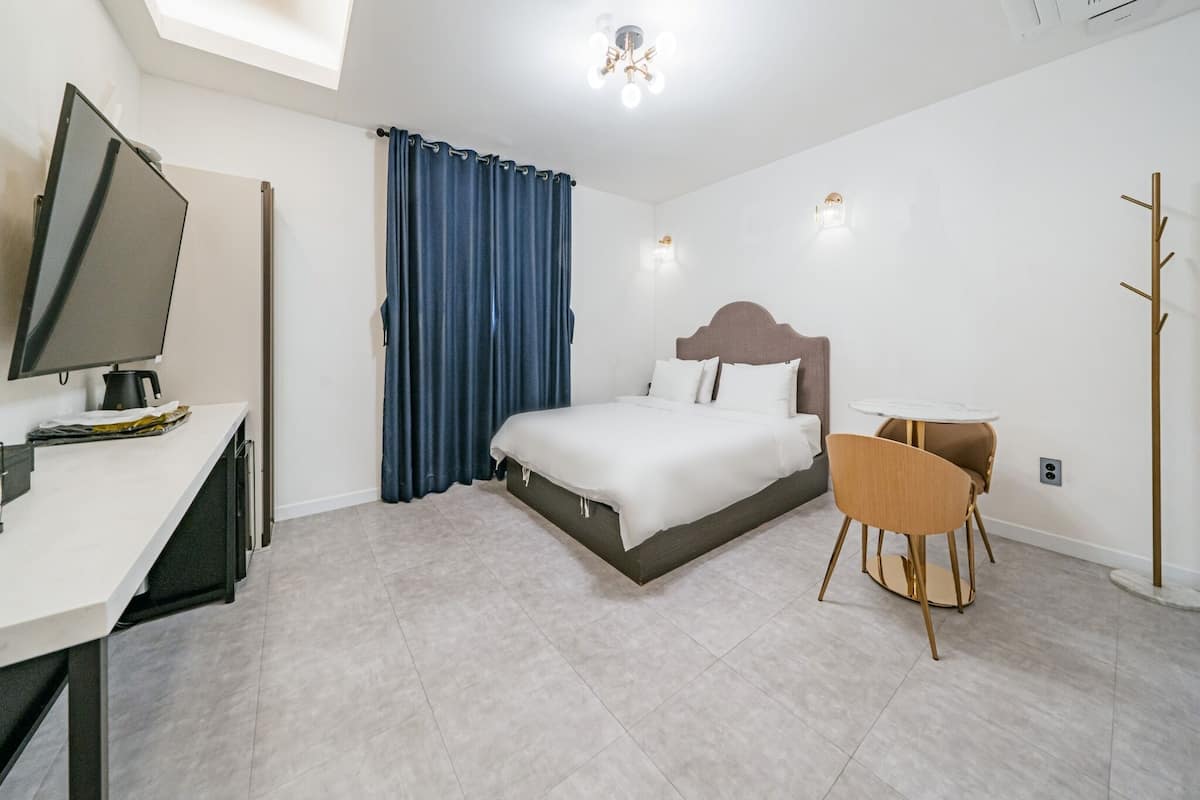 Habitación de hotel moderna con una cama, un escritorio, una silla y un perchero.