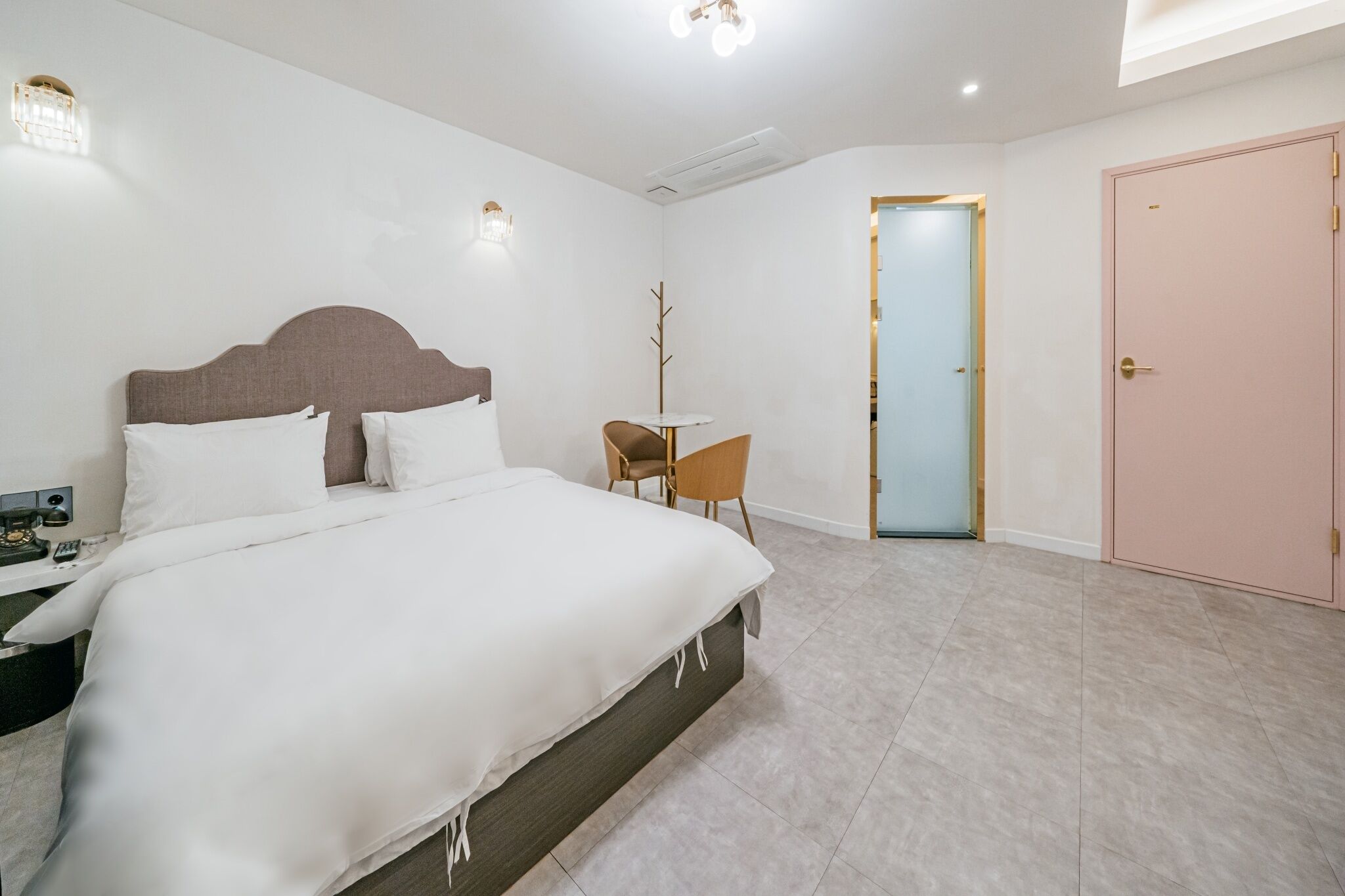 A modern hotel room with a large bed, a small table, and a chair.